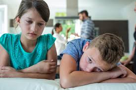 Hypnotherapy for attachment issues. Two sad looking children with arguing parents in the background.